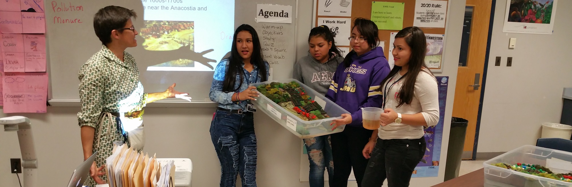 Several high school students standing in front of a classroom presenting their watershed model.