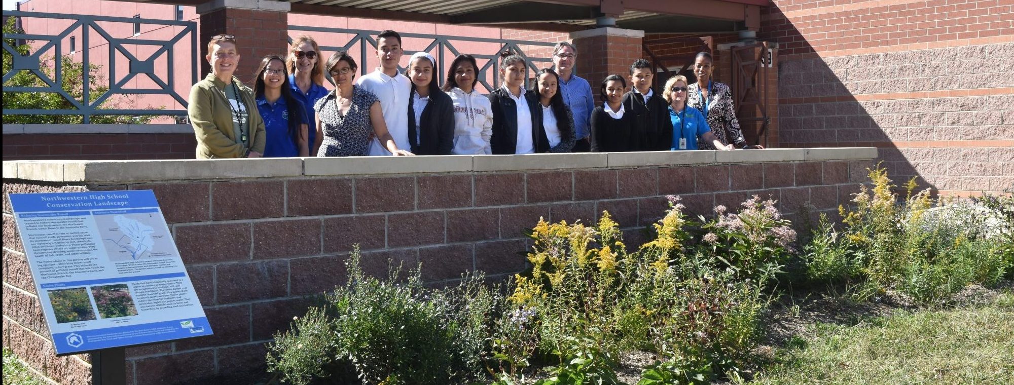 Students and Teachers standing behind a conservation garden.