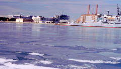 An image of an icy river. A large military ship is in the background.