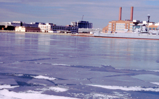 An image of an icy river. A large military ship is in the background.