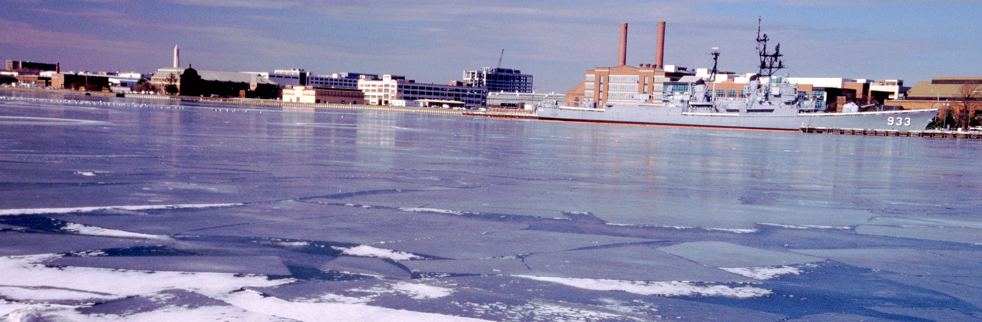 An image of an icy river. A large military ship is in the background.