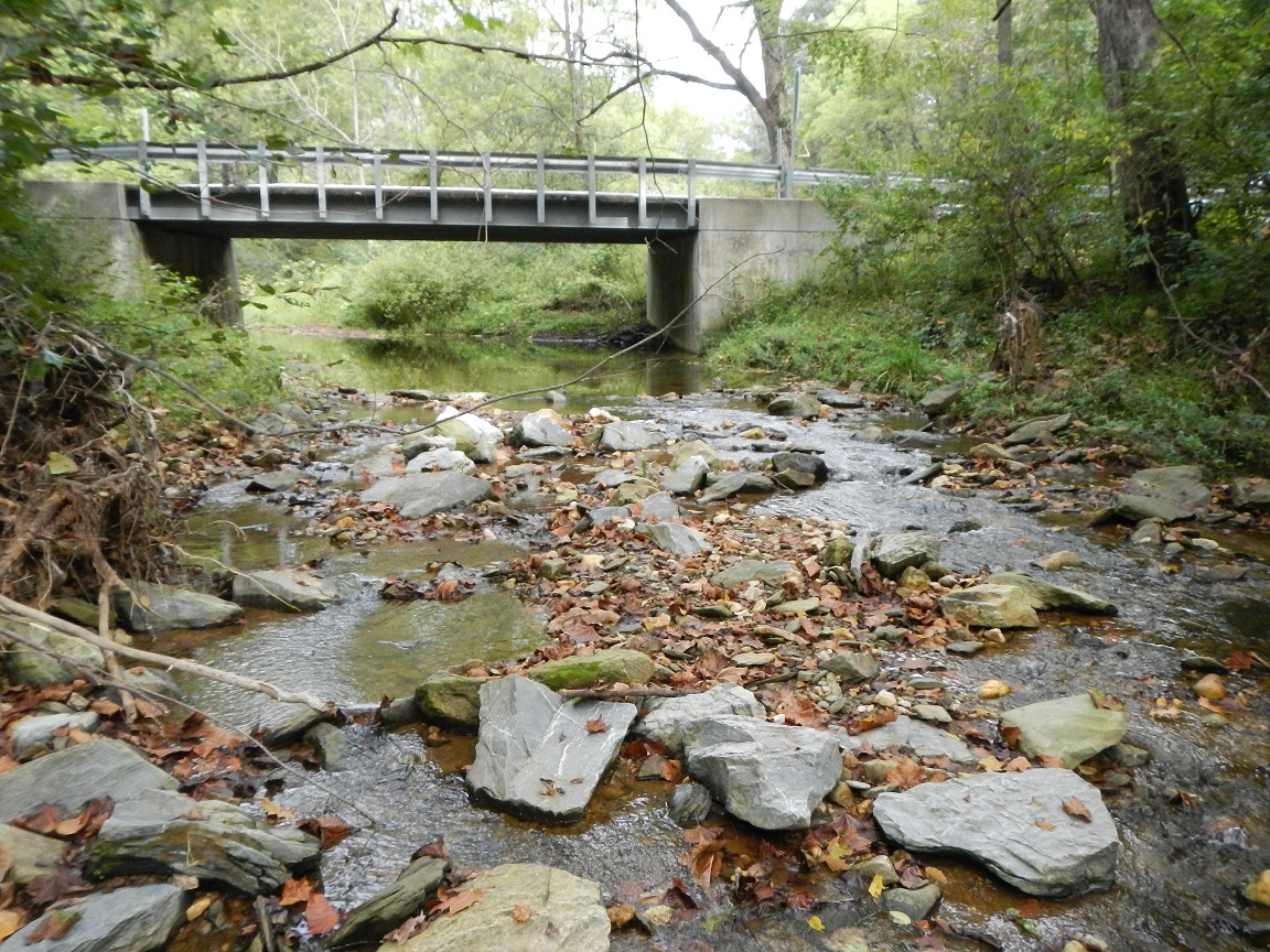 A shallow creek with a concrete bridge over it.