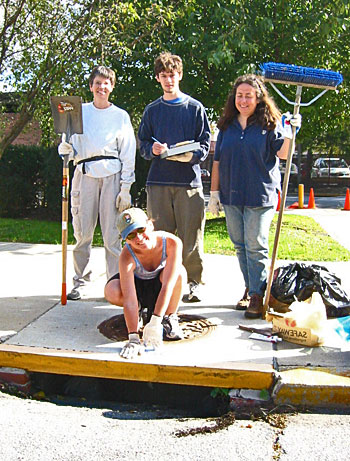 Four youths standing on top of an unpainted stormdrain.
