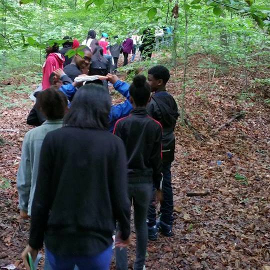 A line of students in a forested area on their campus.