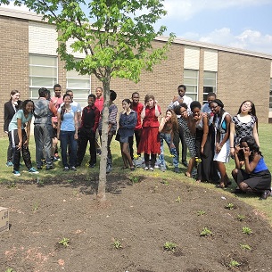 Students and teachers surrounding a freshly dug up lawn.