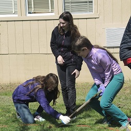 Three people in the schoolyard, planting a tree.