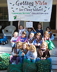 About 20 girl scouts posing under a banner that says "Getting Nuts for Clean Water".
