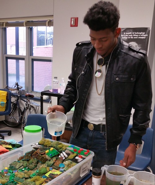Student pouring water on the watershed model.
