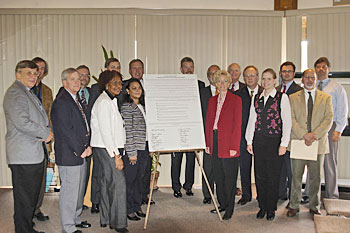 A group of people posing with a large sheet of paper.
