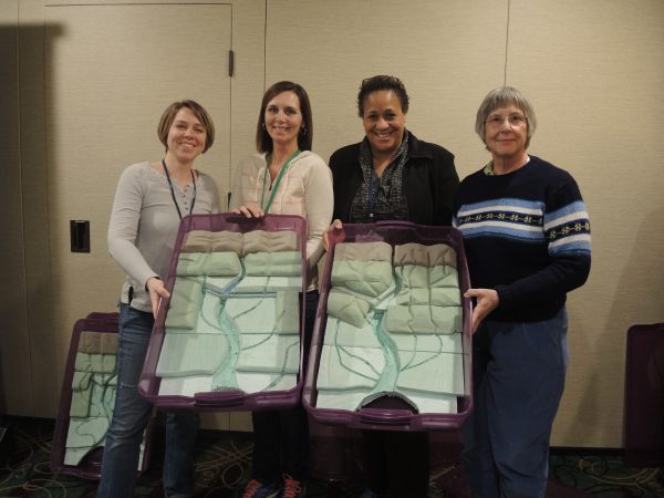 Four teachers holding up two watershed models.