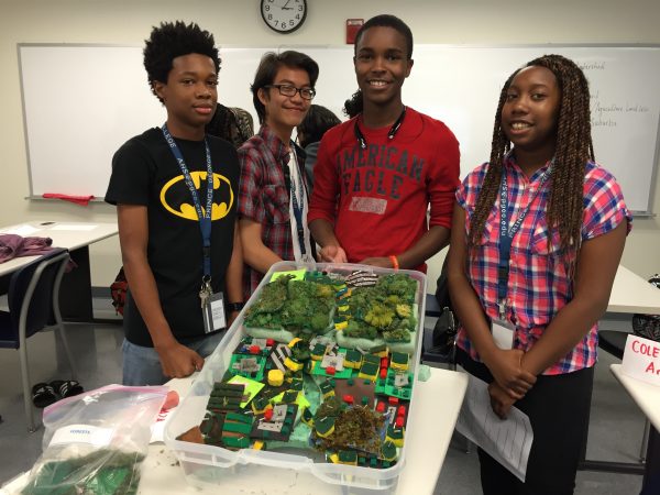 A group of four students holding up a completed watershed model.