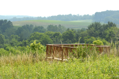 A viewing platform in the middle of a meadow, overlooking valleys.