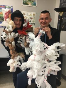 Two male students putting their plastic-bag chains on display