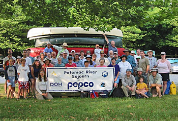 A large group of people standing behind a banner that says "Potomac River Sojourn".