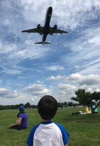 A little boy watches a large plane fly directly overhead. 