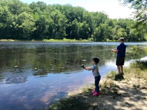 A boy and his father are fishing in a pond at Cedarville State Park. 