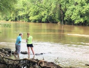 Two women stand next to a large river.