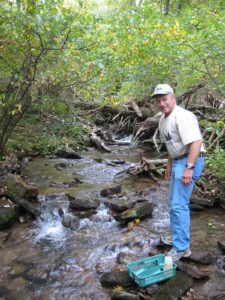 Man stands by a creek. 