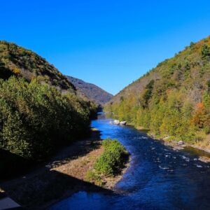 A large river nestled between two forested mountains.