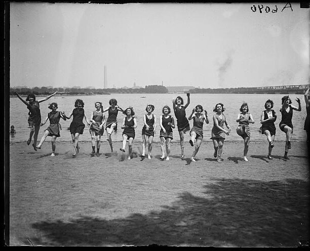 A line of women in old fashioned swimsuits along the Potomac River in Washington, D.C>