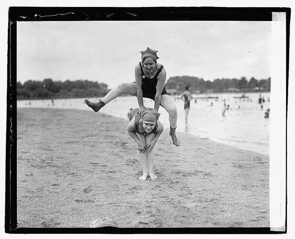 Two women play leapfrog in old fashioned bathing suits along the tidal basin / Potomac River.