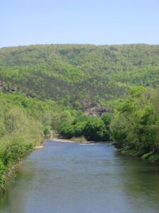 A river with forested mountains on each side. Mill Run at Nathaniel Mountain WMA. 